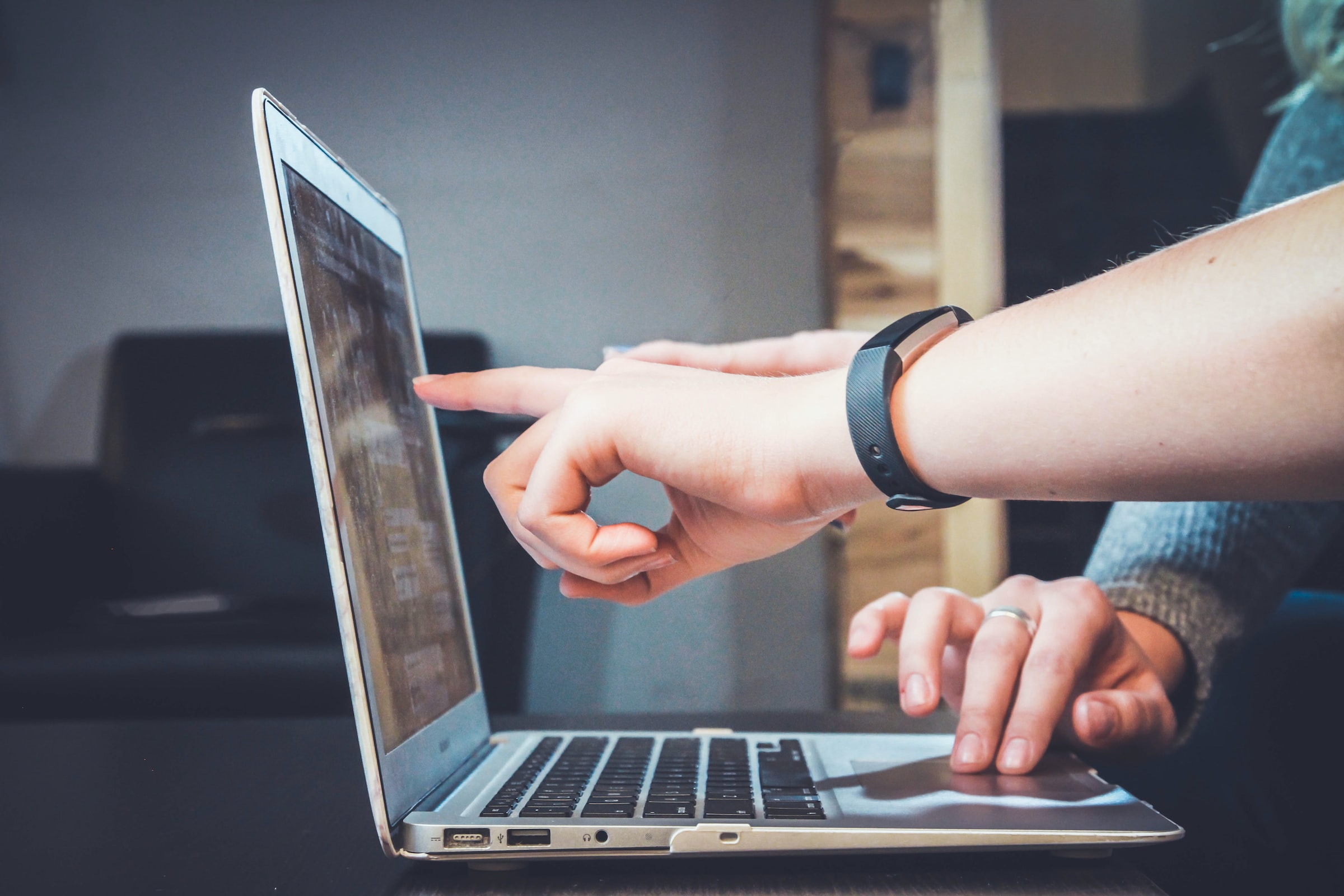 a person pointing at a laptop screen